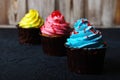 Cupcake cakes yellow, pink, blue on a dark background