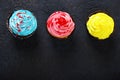 Cupcake cakes yellow, pink, blue on a dark background