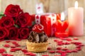 Cupcake with cherry in front of bouquet of red roses Royalty Free Stock Photo