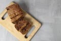 A cupcake chocolate loaf cut into pieces lies on a wooden board tray. Still life with a cupcake on a gray background and a tray. Royalty Free Stock Photo