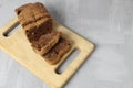 a cupcake chocolate loaf cut into pieces lies on a wooden board tray. Still life with a cupcake on a gray background and a tray. Royalty Free Stock Photo