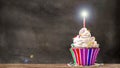 Cupcake with cream and candle with a blackboard background.