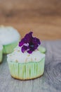 Cupcake decorated with meringue and violet flower and lime peel