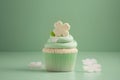 Cupcake with green cream and white flowers on pastel green background