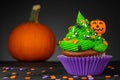 Cupcake on Halloween. Carved pumpkin Jack o lantern. Dessert on Halloween party. Muffin decorated with colored sprinkles Royalty Free Stock Photo