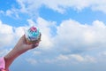 Cupcake in hand on blue sky background