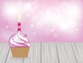 Cupcake with pink candle on wooden planks