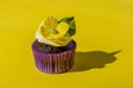 Cupcake in purple wrap on solid yellow background with strong shadow. Pop art. Trendy funky minimalist style