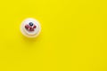 Cupcake with whipped cream and berries, confectionery products on a yellow background.