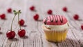 Cupcakes with berry cream decorated with chocolate on a wooden table with cherries. Royalty Free Stock Photo