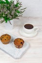 Cupcakes with black currants on a white wooden cutting board against the background of a cup of tea. Royalty Free Stock Photo