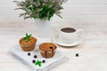 Cupcakes with black currants on a white wooden cutting board against the background of a cup and mint flowers. Royalty Free Stock Photo