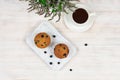 Cupcakes with black currants on a white wooden cutting board against the background of a cup of tea. View from above. Royalty Free Stock Photo