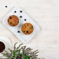 Cupcakes with black currants on a white wooden cutting board against the background of a cup of tea. View from above. Royalty Free Stock Photo
