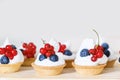 Cupcakes with cream and fresh berries. Cakes with cream, strawberries, blueberries on table in kitchen Royalty Free Stock Photo