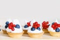 Cupcakes with cream and fresh berries. Cakes with cream, strawberries, blueberries on table in kitchen Royalty Free Stock Photo