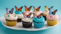 Cupcakes with cream and sugar butterflies and birthday candles on a white plate. Royalty Free Stock Photo