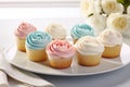 Cupcakes decorated with pink and blue frosting and roses on a plate, Delight in a collection of beautifully crafted cup, AI