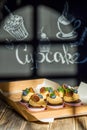 Cupcakes with fruits and berries in a box on a wooden table, a wall with chalk drawings, different light effects