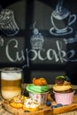 Cupcakes with fruits and berries and coffee on a wooden table, a wall with chalk drawings, different light effects