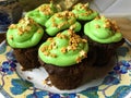 Cupcakes with green frosting and golden stars sprinkles on a white plate