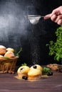 Cupcakes with mint and blackcurrant leaves in powdered sugar on a black background, a wooden basket with cupcakes and Royalty Free Stock Photo