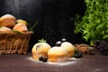 Cupcakes with mint and blackcurrant leaves in powdered sugar on a black background, a wooden basket with cupcakes and Royalty Free Stock Photo