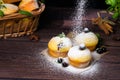 Cupcakes with mint and blackcurrant leaves in powdered sugar on a black background, a wooden basket with cupcakes and Royalty Free Stock Photo