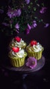 Cupcakes with strawberry on dark wooden table.