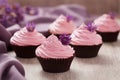 Cupcakes traditional sweet wedding pastry with pink cream and violet flowers in row on vintage background