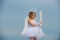 Cupid cute girl with a bow. A beautiful teen with blonde curly hair and a bow and arrow as cupid - Valentines Day. Bow Royalty Free Stock Photo