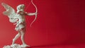 Cupid statue aiming arrow against red background