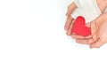 Cupped hands with bandage holding a red heart in white background. Sacrificial and selfless love and genuine kindness concept.