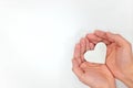 Cupped hands holding a white heart in white background. Kindness and pure love concept. Royalty Free Stock Photo