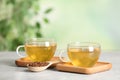 Cups of buckwheat tea and granules on table against blurred background. Space for text