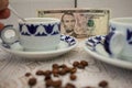 cups of coffee and coffee beans on the table in front of a dollar bill Royalty Free Stock Photo