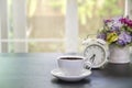 Cups of coffee blurred alarm clock and vase with beautiful flower bouquet  on table in coffee shop Royalty Free Stock Photo