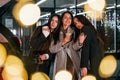 Cups of drink in hands. Three cheerful women spends Christmas holidays together outdoors. Conception of new year Royalty Free Stock Photo