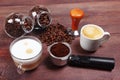 Cups of espresso and cappuccino, holder with ground coffee, tamper and coffee beans on table Royalty Free Stock Photo