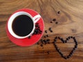 A cups of hot black coffee and love sign of raw coffee beans decoration. On wooden background table in high angle view. Royalty Free Stock Photo