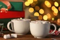 Cups of hot cocoa with marshmallows on table against blurred background Royalty Free Stock Photo