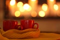 Cups of hot drink on knitted scarf against background. Winter atmosphere Royalty Free Stock Photo