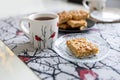 Cups and a napkin with a pattern of bullfinches and Viennese cookies on a plate on the table. Kitchen set. Royalty Free Stock Photo