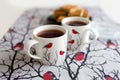 Cups and a napkin with a pattern of bullfinches and Viennese cookies on a plate on the table. Kitchen set. Royalty Free Stock Photo