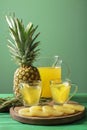 Cups with pineapple juice on green table