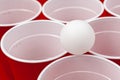 Cups and plastic ball on red background. Beer pong game Royalty Free Stock Photo