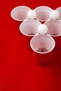 Cups and plastic ball on red background. Beer pong game Royalty Free Stock Photo