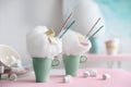 Cups of tasty cotton candy dessert and marshmallow on table, space for