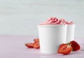 Cups with tasty frozen yogurt and strawberries on table. Space for text