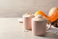 Cups with tasty pumpkin spice latte on gray table